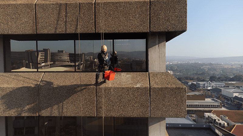 Rope access worker scaling skyscraper to perform Window Cleaning