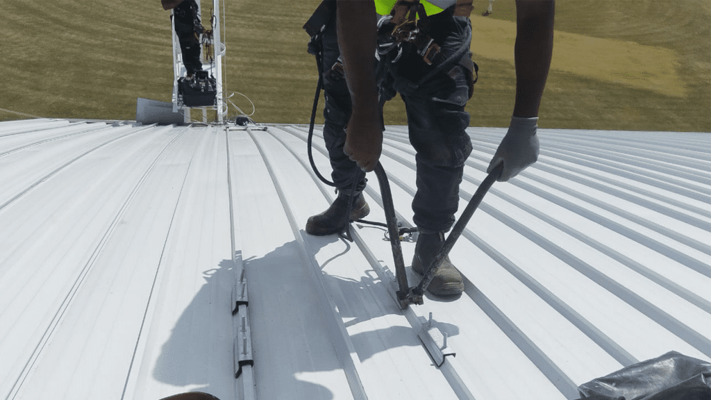 Rope access technician installing a permanent horizontal lifeline system during roof safety installation at St Charles College in Pietermaritzburg.