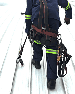 Rope access technician connected to a permanent roof lifeline system during fall protection installation at St Charles College.