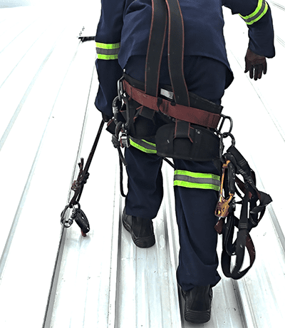 Rope access technician connected to a permanent roof lifeline system during fall protection installation at St Charles College.