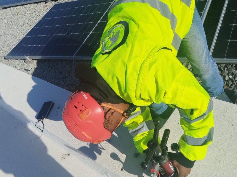 Technician verifying anchor strength using load-testing equipment during rooftop Anchor Point Testing.