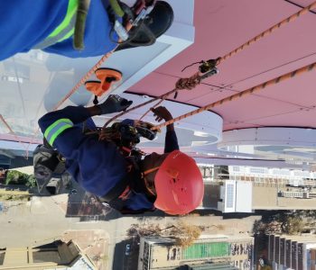 Rope Access Signage Repair Johannesburg with technician suspended above the ABSA Tower sign during maintenance. Signage Repairs & Installation