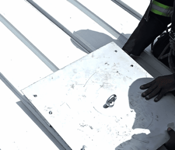 Rope access technicians installing and securing a roof anchor point for a permanent fall protection system.