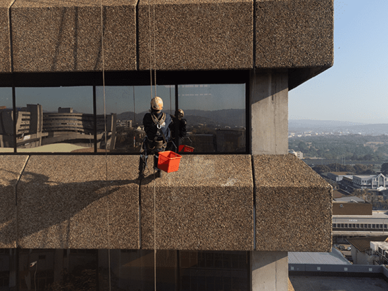 Rope access worker scaling skyscraper to perform Window Cleaning